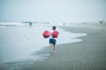 Happy boy plays with red balloons on the beach having great holidays time on summer. Lifestyle, vacation, happiness, joy concept Royalty Free Stock Photo