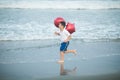 Happy boy plays with red balloons on the beach having great holidays time on summer. Lifestyle, vacation, happiness, joy concept Royalty Free Stock Photo