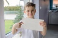 Happy boy in a polo shirt, holding an empty copyspace sheet of paper Royalty Free Stock Photo