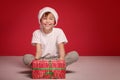 Happy boy posing in Santa Claus hat on red studio background. Christmas concept Royalty Free Stock Photo