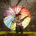 Happy boy with a rainbow umbrella in park Royalty Free Stock Photo