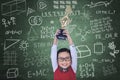 Happy boy raising trophy in class Royalty Free Stock Photo