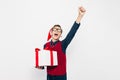 Happy boy in a red Santa hat. Stylish boy with Christmas gift having fun and showing gesture of victory and success on white