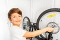 Happy boy repairing his bicycle wheel with spanner