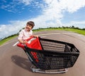 Happy boy riding empty supermarket shopping cart Royalty Free Stock Photo