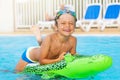 Happy boy riding inflatable toy in the pool