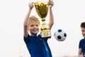 Happy boy rising golden trophy. Child winning sports competition