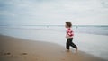 Happy boy running ocean shore barefoot. Cheerful son playing airplane pilot game Royalty Free Stock Photo