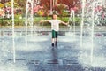 Happy boy running between water jets in city fountain. Summer vacation Royalty Free Stock Photo