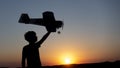 Happy Boy runs with a toy airplane on a field in the sunset light. Children play toy airplane. teenager dreams of flying and Royalty Free Stock Photo