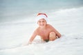 Happy boy in Santa`s hat swims on ocean surfline. Christamas and Royalty Free Stock Photo
