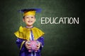 Happy boy with scholar gown and piggy bank Royalty Free Stock Photo