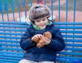 Happy boy sitting on bench playing with doy toy. Cute Kid with smiling face playing with toy in the park, Adorable Child having Royalty Free Stock Photo