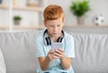 Happy boy sitting on couch, using smartphone Royalty Free Stock Photo