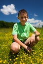 Happy boy sitting on a field of celandine (Ranunculus ficaria