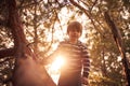 Happy boy sitting high up in a pine tree at sunset Royalty Free Stock Photo