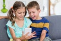 Happy boy sitting on sofa and using mobile phone in living room Royalty Free Stock Photo