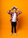 Happy boy smiling at the camera and holding books on his head, on a yellow background Royalty Free Stock Photo