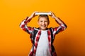 Happy boy smiling at the camera and holding books on his head, on a yellow background Royalty Free Stock Photo