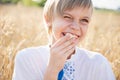 Happy boy smiling and laughing in summer day at nature. cute child in wheat field on warm summer day with a piece of bread