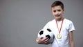 Happy boy smiling with winner medal on chest, holding soccer ball, champion Royalty Free Stock Photo