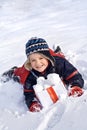 Happy boy in the snow with snowballs in a box