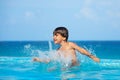 Happy boy splashing water around him in pool Royalty Free Stock Photo