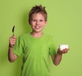 Happy boy with spoon and healthy organic yogurt isolated on gree