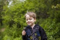 A happy boy on a spring day in the garden blows on white dandelions, fluff flies off him. The concept of outdoor recreation in Royalty Free Stock Photo