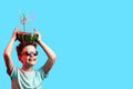 A happy boy in sunglasses holding watermelon with cocktail tubes on head on blue background Royalty Free Stock Photo