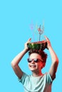 A happy boy in sunglasses holding watermelon with cocktail tubes on head on blue background Royalty Free Stock Photo