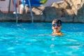 A happy boy in swimming goggles and arm ruffles in an outdoor pool. Royalty Free Stock Photo