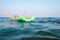 Happy boy swims on green inflatable mattress Royalty Free Stock Photo