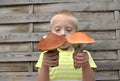 Boy with syndrome down holding two big mushrooms. Royalty Free Stock Photo