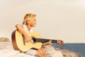 Happy boy teenager playing guitar at the seaside Royalty Free Stock Photo