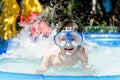 Happy boy in an underwater mask swimming in the pool