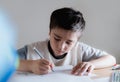 Happy boy using grey colour pen drawing or sketching on paper,Portrait kid siting on table doing homework in living room,Child