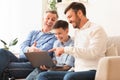 Boy Using Laptop Sitting Between Father And Grandfather On Couch Royalty Free Stock Photo