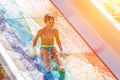 A happy boy on water slide in a swimming pool having fun during summer vacation in a beautiful aqua park. A boy Royalty Free Stock Photo