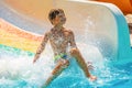 A happy boy on water slide in a swimming pool having fun during summer vacation in a beautiful aqua park. A boy Royalty Free Stock Photo