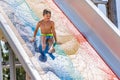 A happy boy on water slide in a swimming pool having fun during summer vacation in a beautiful aqua park. A boy Royalty Free Stock Photo