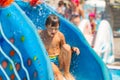 A Happy Boy On Water Slide In A Swimming Pool Having Fun During Summer Vacation In A Beautiful Aqua Park. A Boy