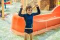 Happy boy on water slide in a swimming pool having fun during summer vacation in a beautiful tropical resort Royalty Free Stock Photo