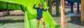 Happy boy on water slide in a swimming pool having fun during summer vacation in a beautiful tropical resort BANNER Royalty Free Stock Photo