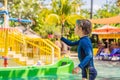 Happy boy on water slide in a swimming pool having fun during summer vacation in a beautiful tropical resort Royalty Free Stock Photo