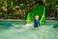 Happy boy on water slide in a swimming pool having fun during summer vacation in a beautiful tropical resort Royalty Free Stock Photo