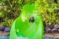 Happy boy on water slide in a swimming pool having fun during summer vacation in a beautiful tropical resort Royalty Free Stock Photo