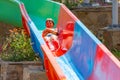 A Happy Boy On Water Slide In A Swimming Pool Having Fun During Summer Vacation In A Beautiful Aqua Park. A Boy