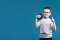 Happy boy in a white t-shirt thinking and looking up with a alarm clock pointing his finger up on a blue background Royalty Free Stock Photo