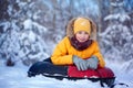 Happy boy in winterwear smiling riding a tubing in winter park. Boy kid play outdoors in snow. Child sledding